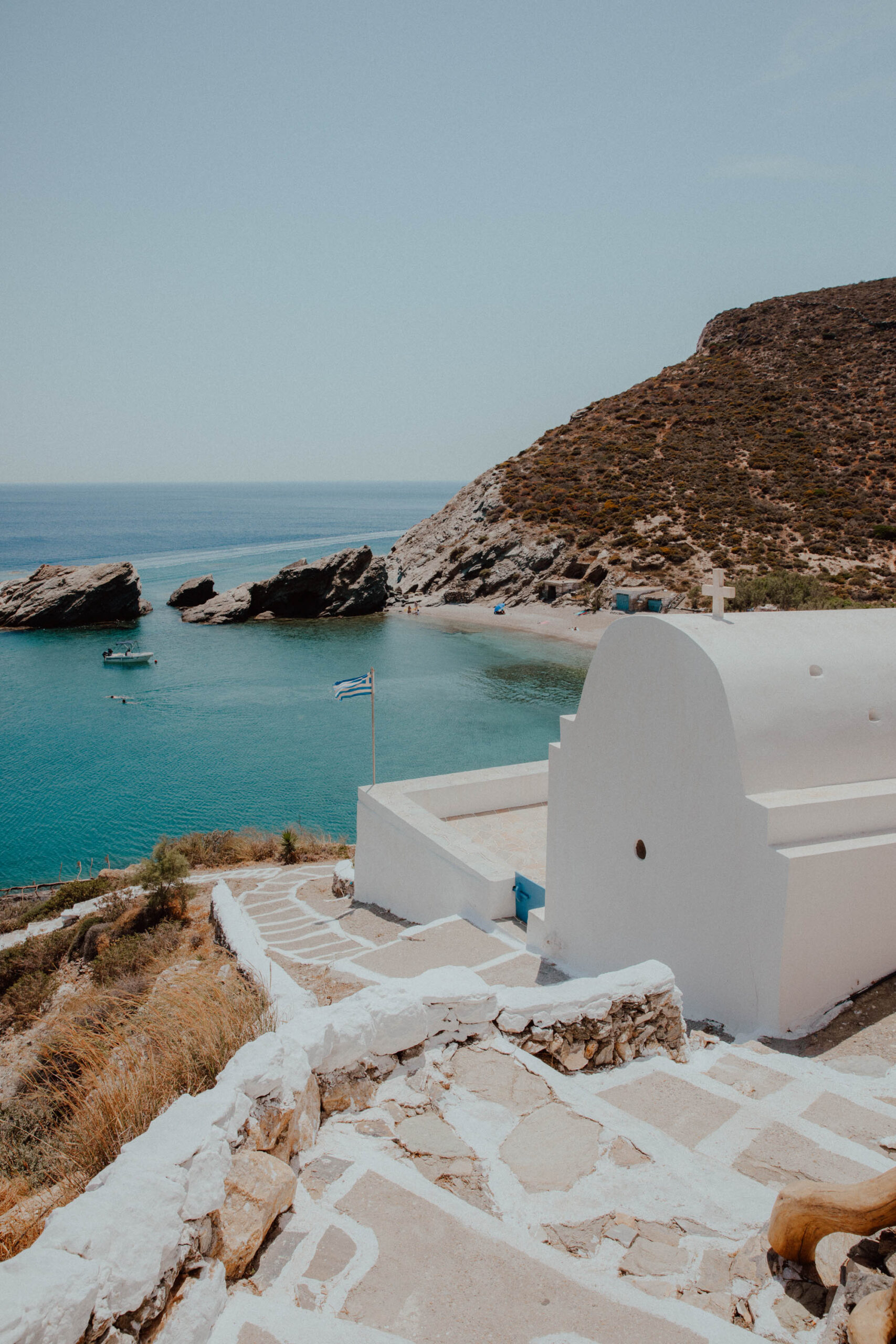 White-washed church overlooking Agios Nikolaos Beach Folegandros with turquoise waters and typical Cycladic architecture