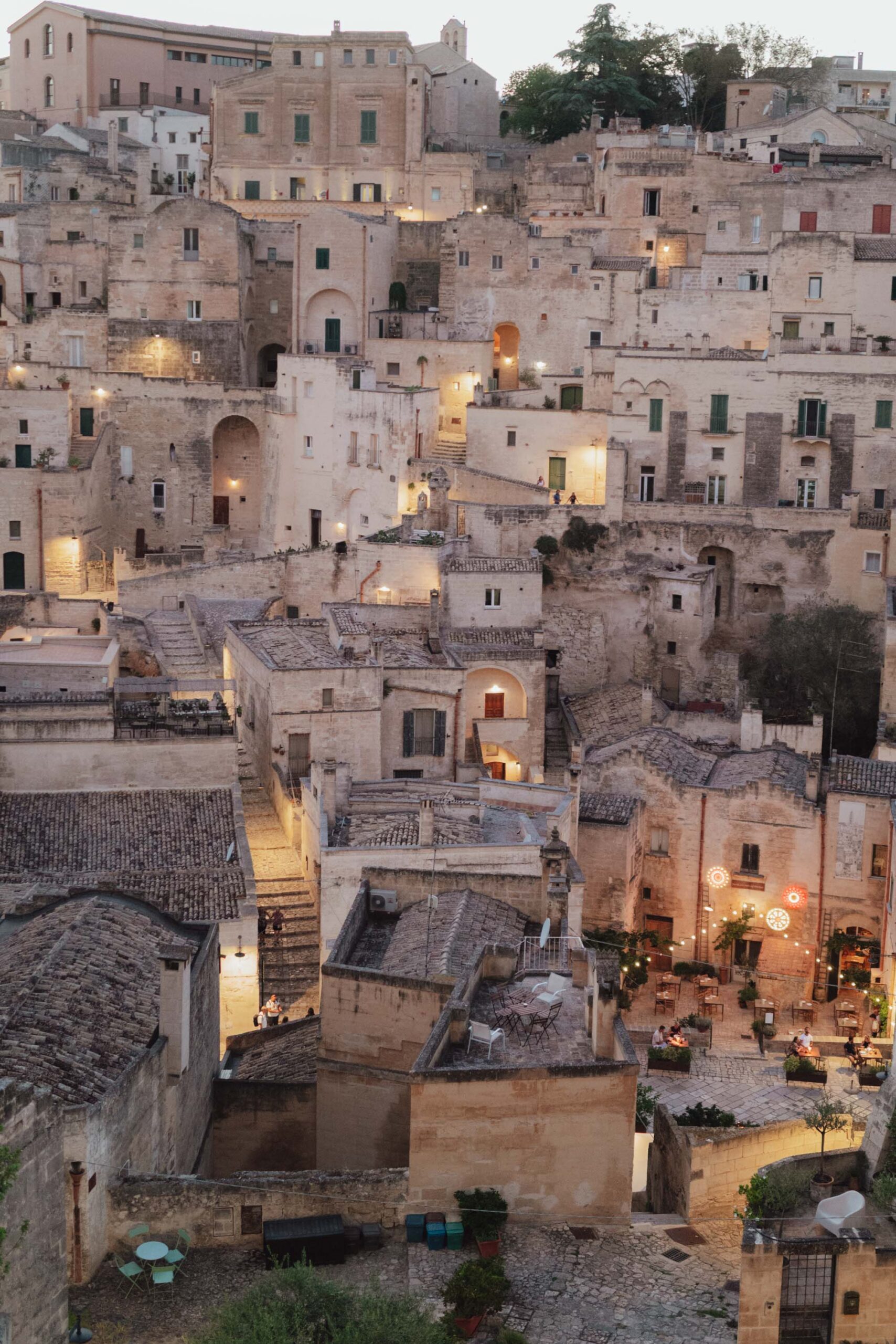 Sunset over matera's rooftops and stone buildings in Italy with lights on