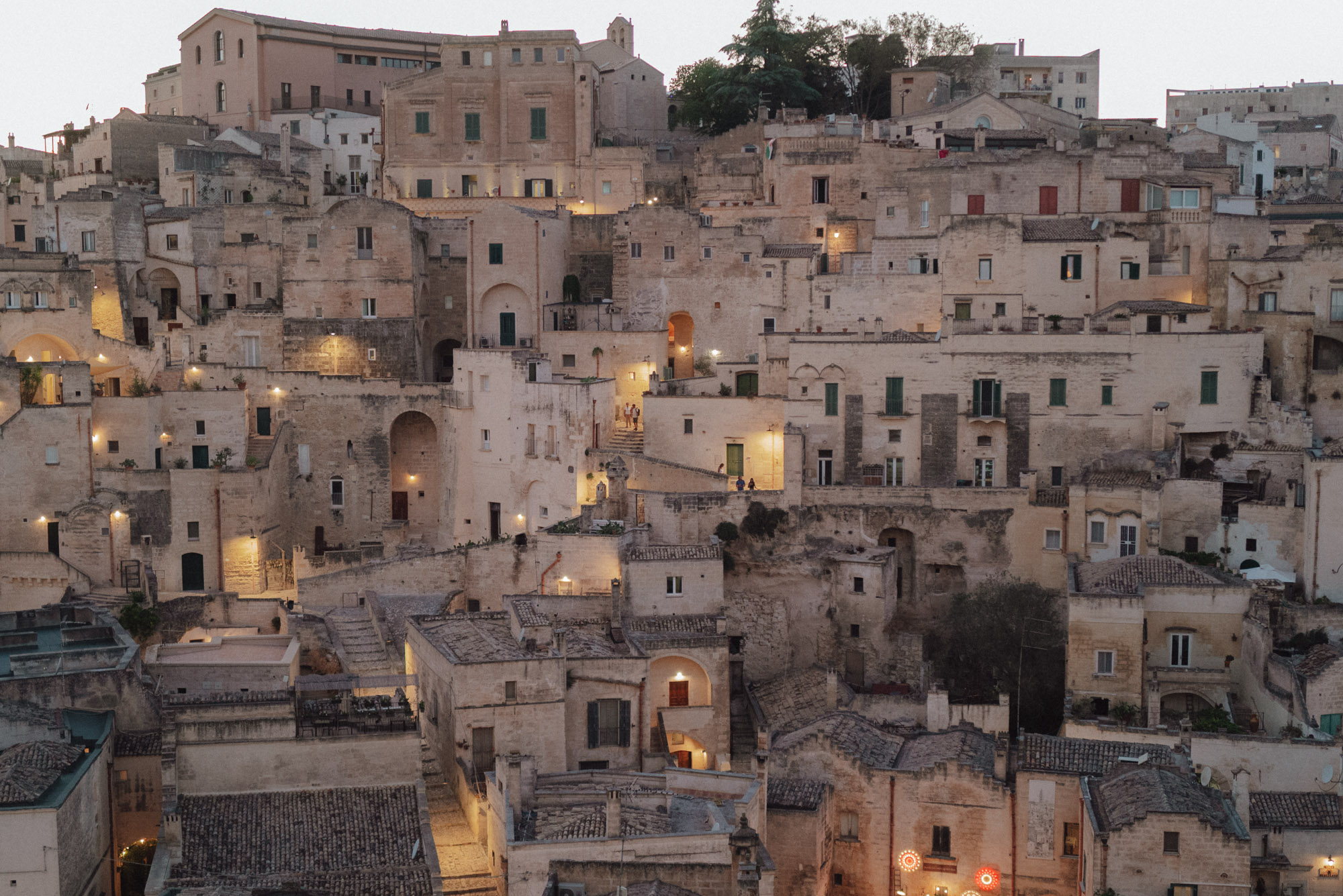 rooftops and stone buildings in Matera's old town at sunset with twinkle lights