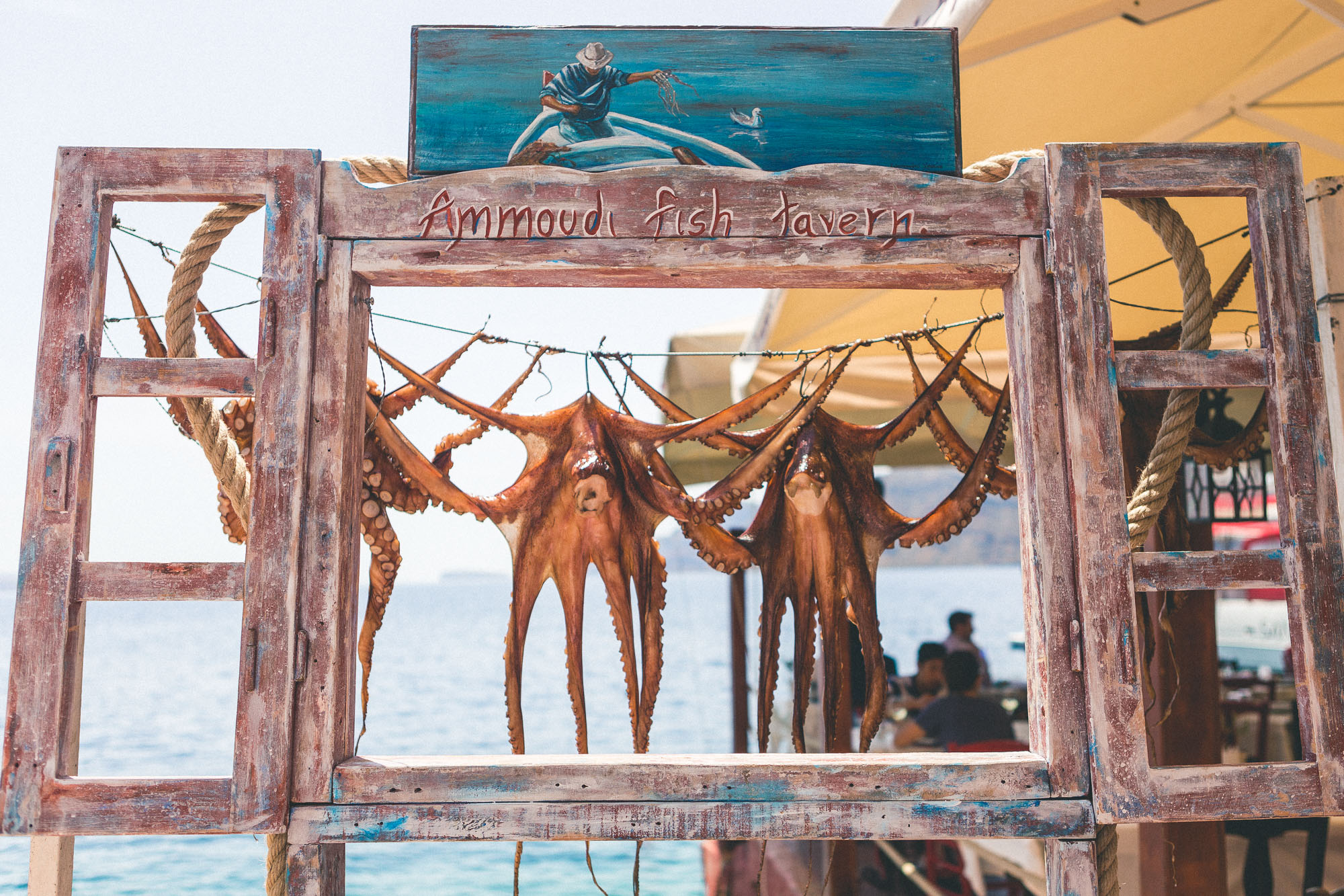 Traditional Greek taverna in Santorini with rustic wooden decor and hanging dried herbs.
