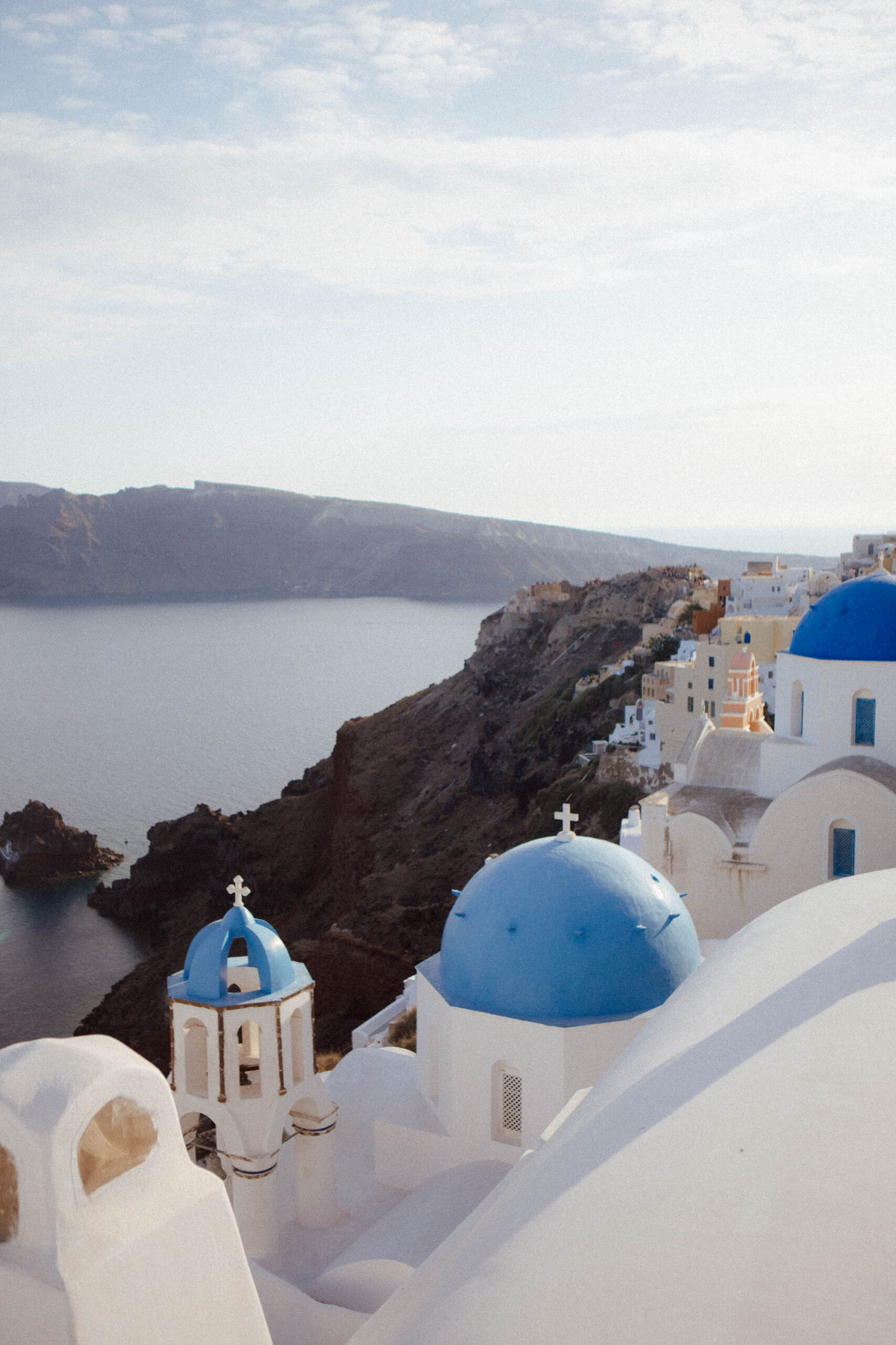 Iconic blue-domed church overlooking the Aegean Sea in Santorini, Greece at golden hour