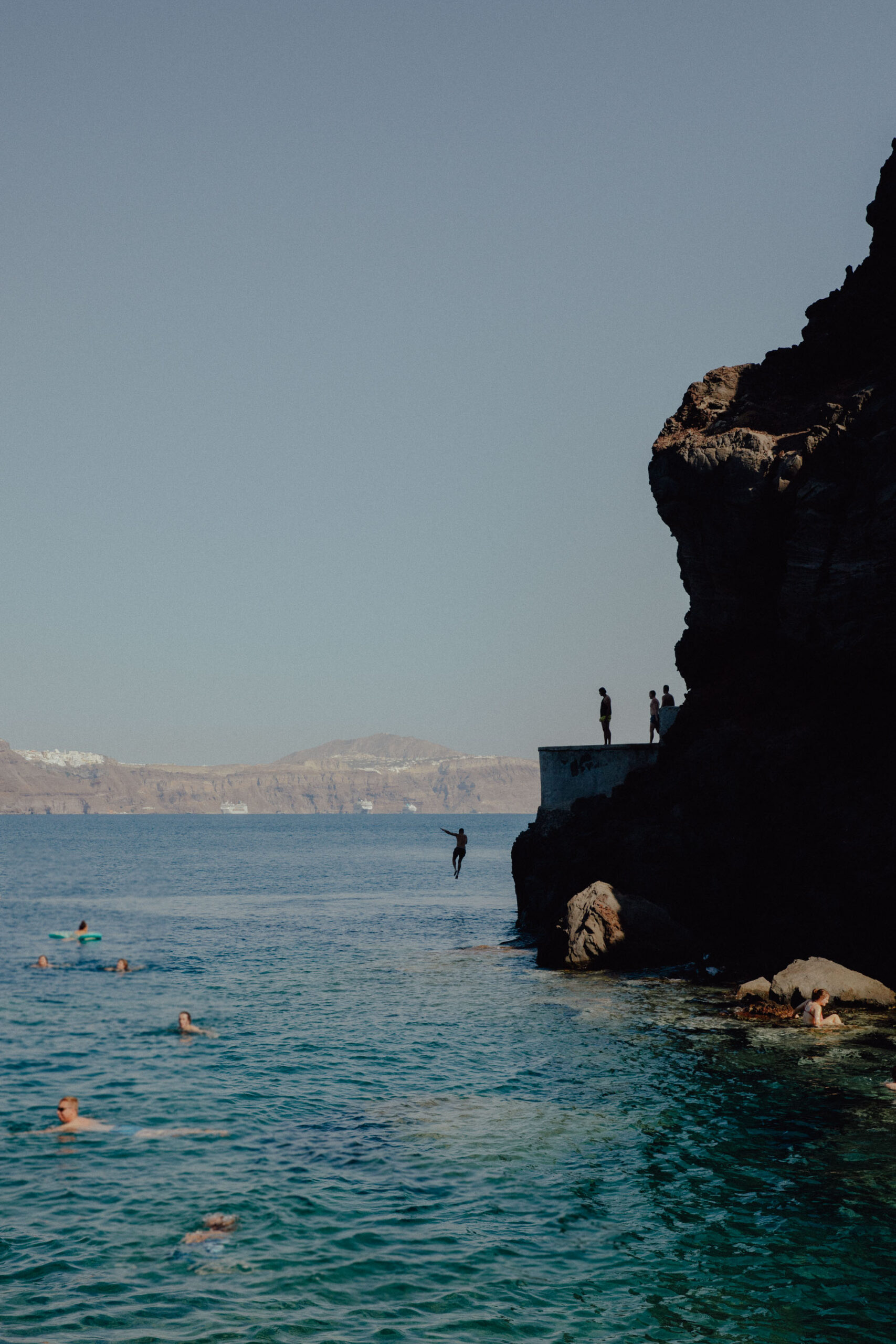 Agios Rock in Santorini, Greece, surrounded by clear blue waters under a bright sky.
