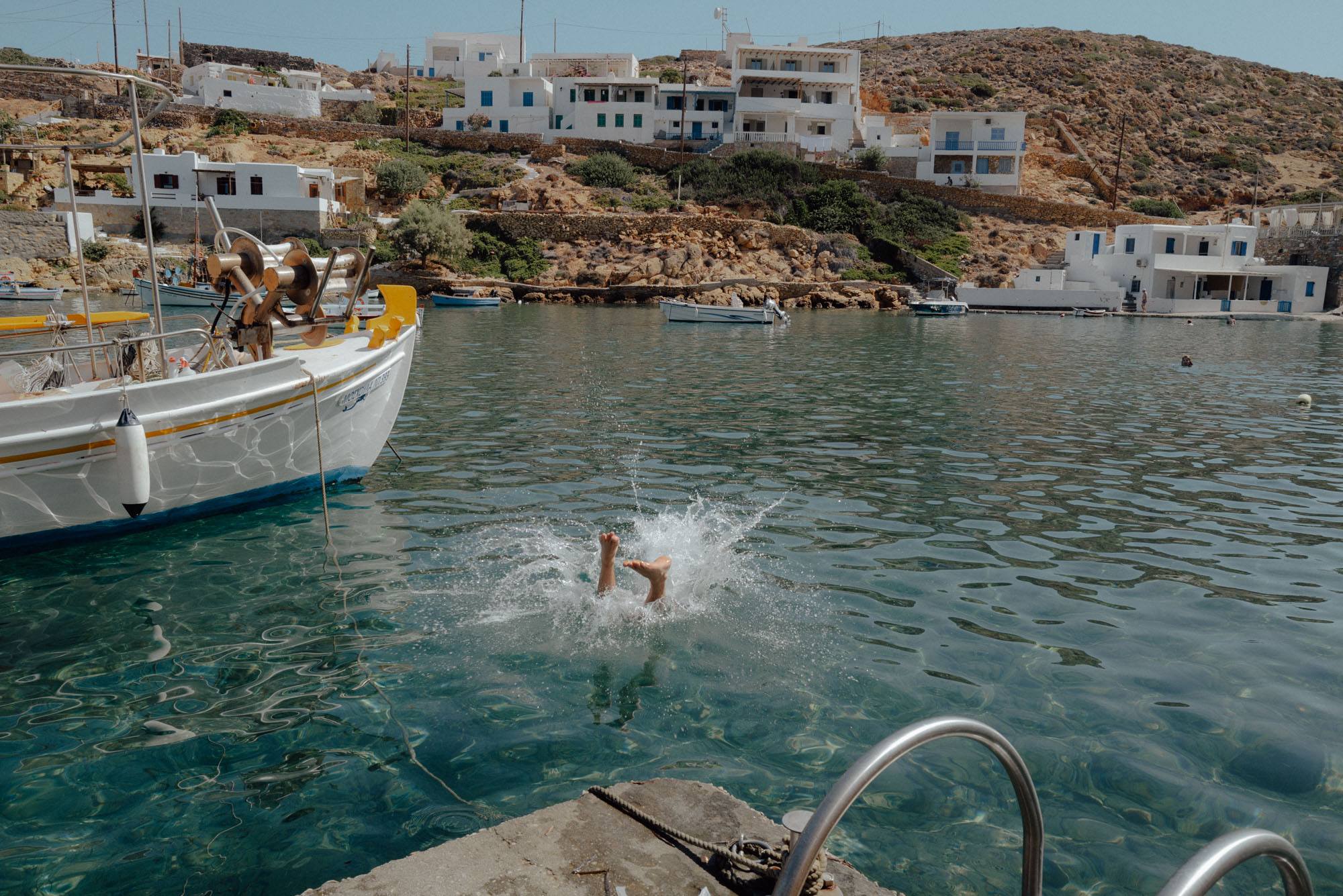 Fishing boats anchored at Cheronissos Beach in Sifnos and a swimmer
