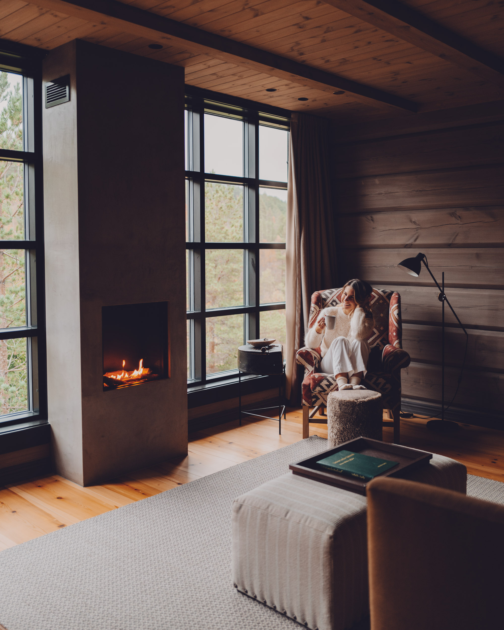 Cozy room interior at Storfjord Hotel in Skodje, Norway with large windows framing spectacular fjord views and mountains beyond